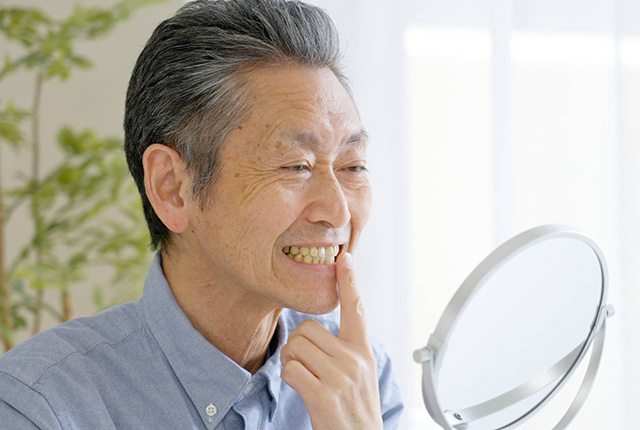 鏡で歯を見る男性